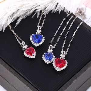 Macro shot of red and blue heart-shaped necklaces on black jewelry box with white feather