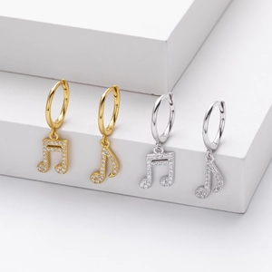 Detailed macro view of gold and silver musical note earrings with sparkling pave-set zircons