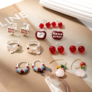 Detail shot of vintage earrings with cherry, rabbit, and kitty charms on magazine backdrop