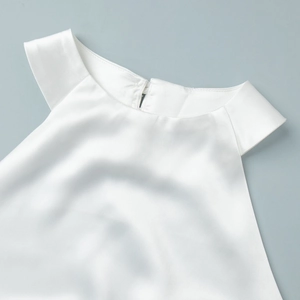 Gros plan du haut bustier en soie blanche montrant la texture satinée et le col