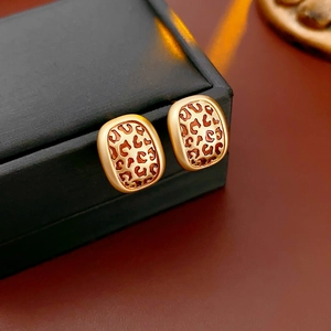 Détail de boucles d'oreilles losanges dorées avec motif léopard en émail rétro chic