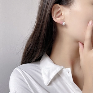 Dettaglio di orecchini a lobo minimalisti in argento spazzolato indossati su modella