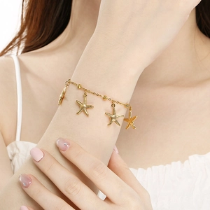Macro shot of gold starfish charms and beads on a stainless steel beach bracelet