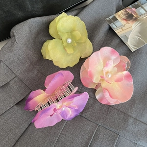 Detail of faux orchid hair claws with ribbon and pearl center in multiple colors