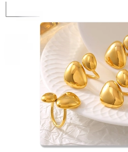 Close-up of irregular pebble shaped golden rings on white textured plate