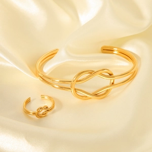 18K gold plated stainless steel knot ring and bangle set on elegant silk fabric