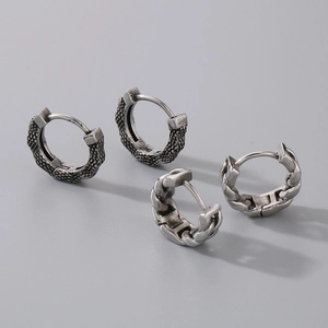 Detailed macro view of vintage silver Cuban chain and snakeskin textured hoop earrings