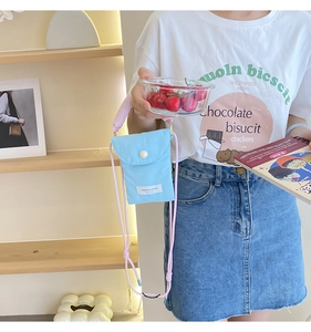Detail of light blue nylon crossbody phone bag with pink strap and white round button