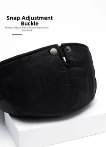 Detail shot of the adjustable snap buckle on a black leather ivy cap with fine texture