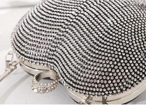 Close-up of heart-shaped clutch bag with shimmering silver rhinestones and chain