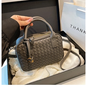 Gray hand-woven leather Boston bag lifted from a luxury gift box with gold hardware