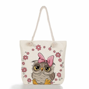 Detail of canvas tote bag showing cute owl print and durable rope handles on cream fabric