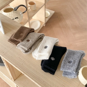 Detail of five pairs of warm knitted socks with floral embroidery in neutral tones