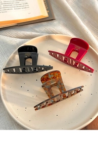 Close-up of three large acetate hair claws in black, red, and tortoiseshell patterns
