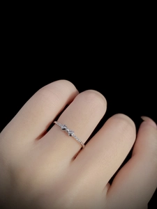 Close-up of a silver bow ring with micro-pave crystals on a model's finger