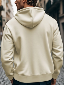 Back view of men's cream beige hoodie in urban street setting showing fabric drape and texture