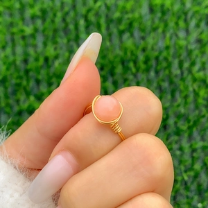 Detailed view of a handmade gold wire-wrapped ring featuring a round pink stone