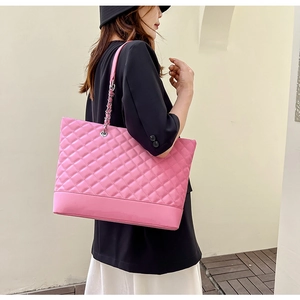 Grand sac cabas matelassé rose avec bandoulière chaîne argentée porté par un modèle
