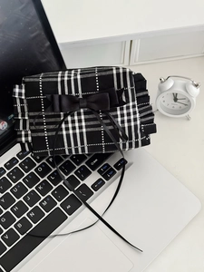 Pochette à carreaux noirs et blancs avec nœud en satin posée sur un clavier d'ordinateur