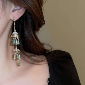 Detail of silver drop earrings featuring blue teardrop beads and ethnic tassel design