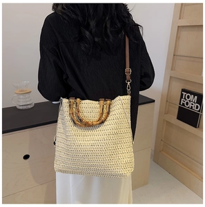 Detailed close-up of beige woven beach bag featuring natural bamboo handles and brown strap