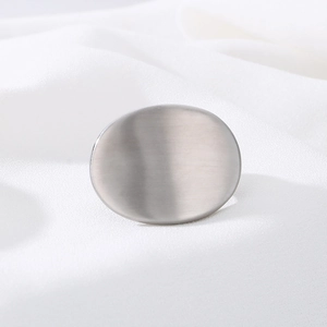 Macro shot of oval stainless steel ring with matte brushed metal texture on satin