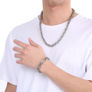 Detailed close-up of silver Byzantine chain necklace and bracelet set on male model