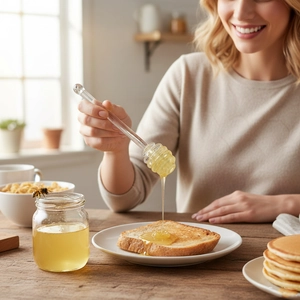 Cuillère à miel en verre transparent utilisée pour remuer du miel dans une cuisine
