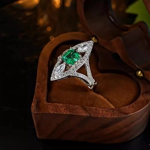 Macro shot of marquise emerald ring with micro-paved diamonds in heart-shaped wooden box
