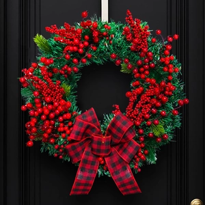 Christmas wreath with red black plaid bow and berries hanging on a black door
