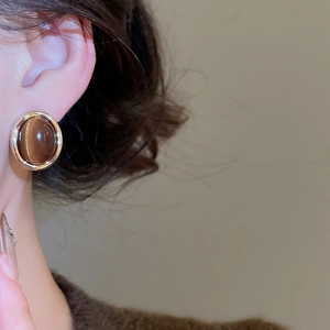 Close-up of 18k gold plated geometric stud earring with brown tiger eye stone on model