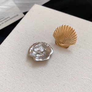 Macro shot of seashell ear cuff details showing gold front and silver back clip