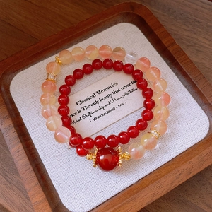 Détail de bracelets en perles d'agate avec espaceurs dorés sur lin et plateau bois