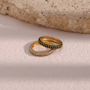 Close-up of gold plated rings with green and clear zircon stones on stone background