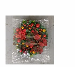 Detail view of a Christmas wreath with red berries and pine cones in clear packaging