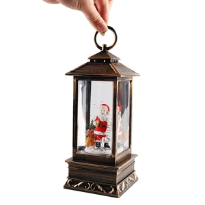 Vintage bronze Christmas lantern with Santa and reindeer scene shown in hand on white background