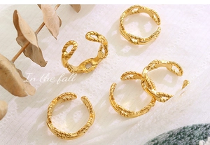 Detail of five 18K gold plated chain rings on white lace with autumn dry leaves