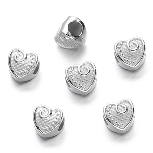 Macro shot of silver heart-shaped spacer beads with spiral texture for jewelry making