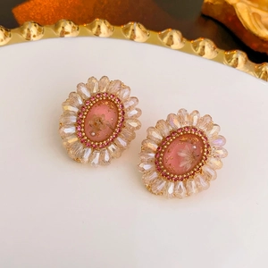 Detail shot of oval floral earrings with pink resin dried flower and crystal beads