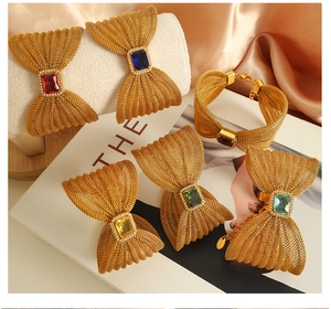 Detail of gold bow bracelet featuring woven mesh and colorful square gemstones