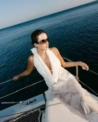 Detail of white deep V-neck beach dress with sunglasses on a luxury yacht deck