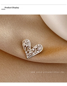 Close-up of heart-shaped silver brooch with cubic zirconia on silk fabric