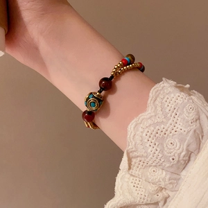 Bracelet ethnique avec perles colorées et clochette dorée sur le poignet d'un mannequin