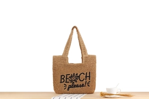 Détail du sac tissé en paille de papier avec lettrage artistique Beach Please en noir