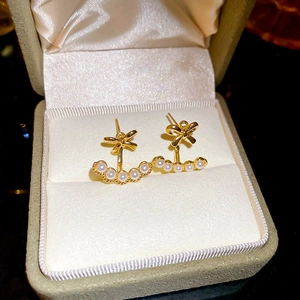 Macro detail of 18k gold plated bow earrings with arc pearls in a jewelry gift box