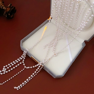 Detail of multi-layer glass pearl body chain with golden chains and tassels on a jewelry box
