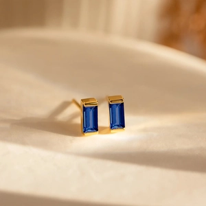 Macro shot of square-cut deep blue zircon earrings with minimalist gold-plated settings