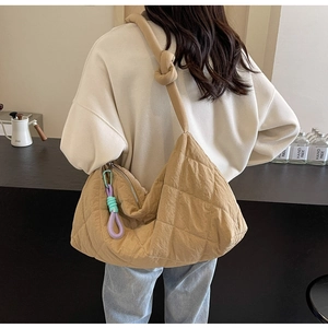 Detail of khaki quilted tote bag featuring a knotted shoulder strap and woven zipper pull