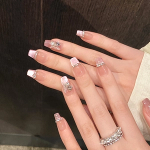 Close-up of pink gradient press-on nails with 3D bows, rhinestones and floral accents