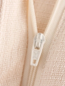 Detail of high-quality beige zipper on textured fabric with a premium engraved logo